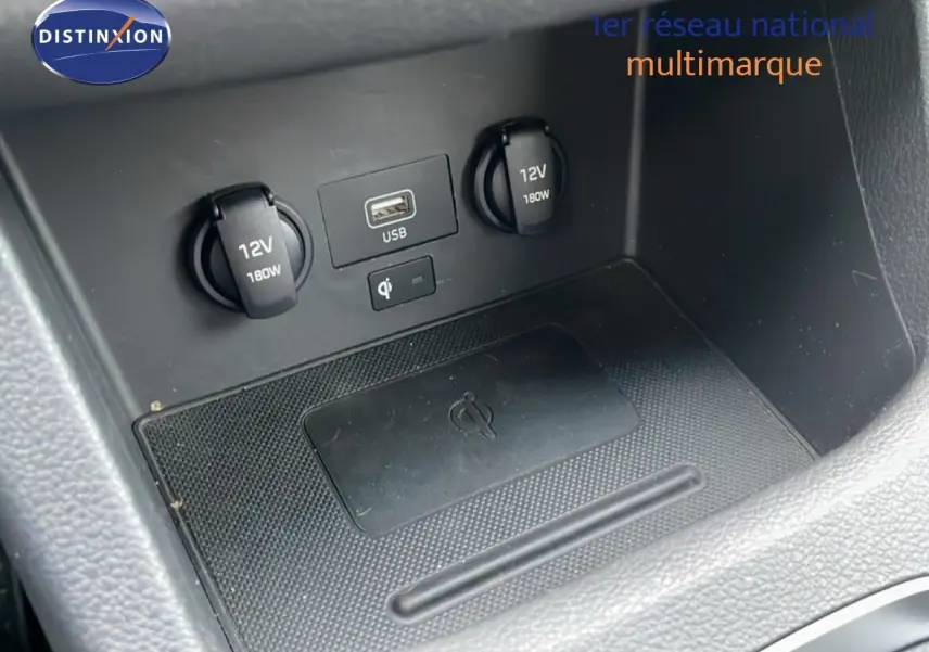 Détail de la console centrale de la Hyundai i30 SW 2023 montrant prises 12V, port USB et zone de recharge sans fil.