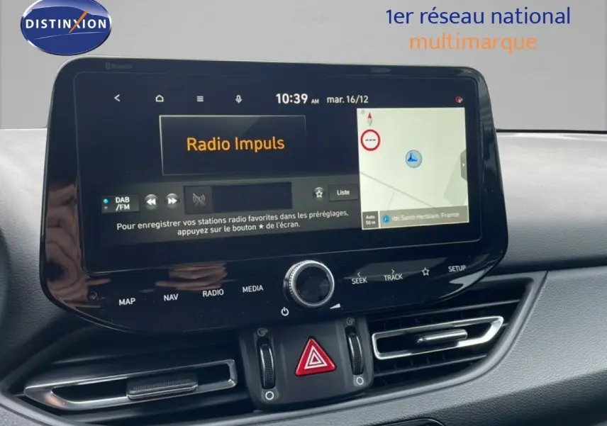 Tableau de bord de Hyundai i30 SW 2023 avec écran tactile central affichant radio et navigation, ambiance intérieure moderne.