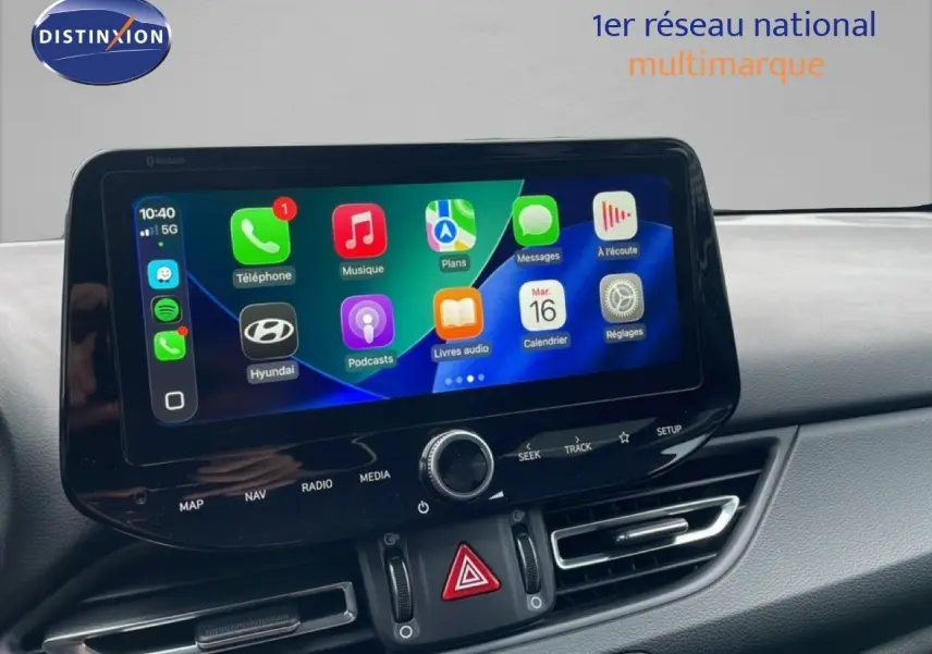Écran tactile central affichant Apple CarPlay dans l’habitacle d’une Hyundai i30 SW blanche, vue de face.