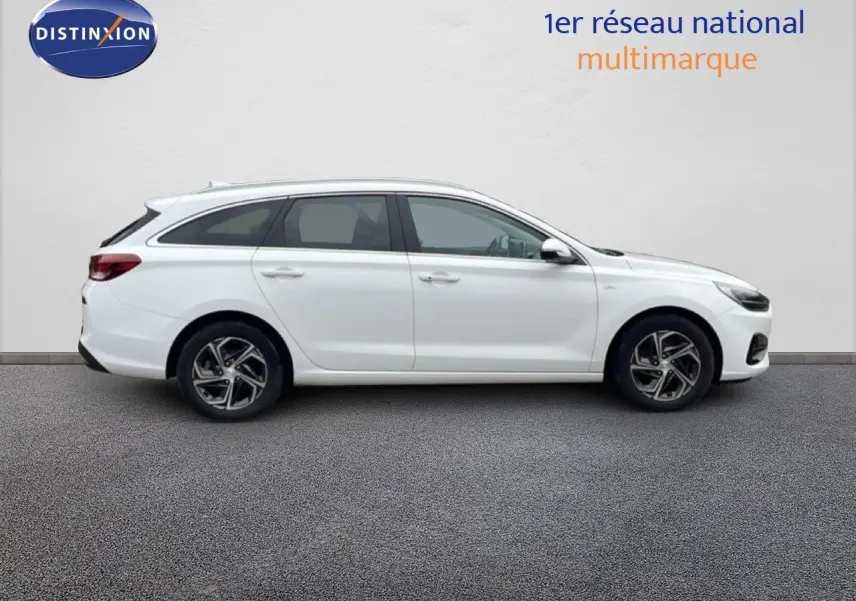 Profil droit d'une Hyundai i30 SW blanche Atlas 2023 avec jantes alliage et lignes épurées.