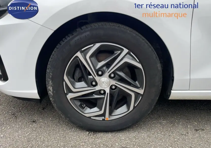 Gros plan sur la roue avant gauche avec jante alliage gris et noir d'une Hyundai i30 SW blanc Atlas.
