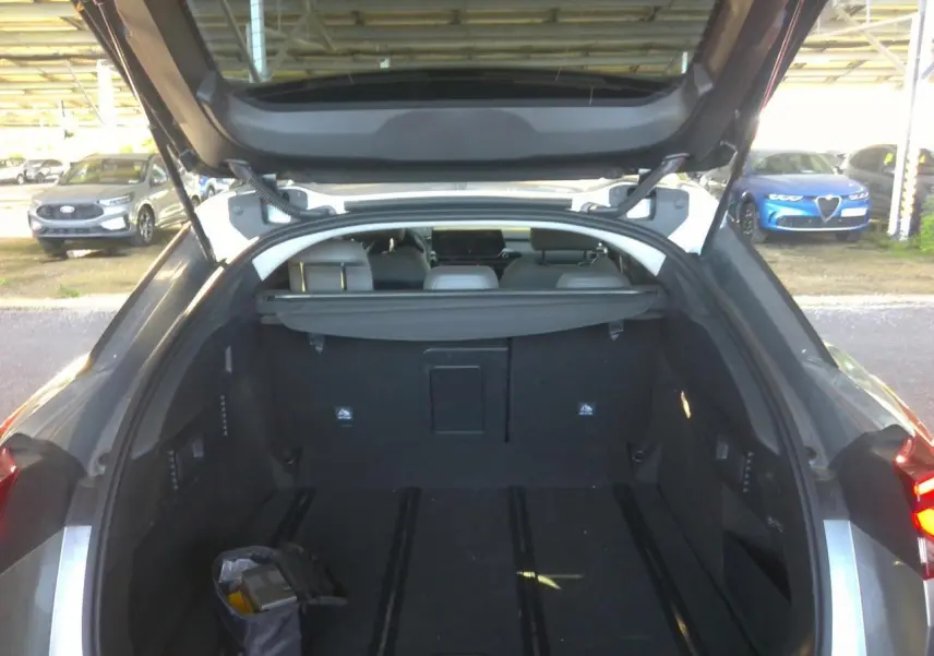 Coffre ouvert vu de l'arrière d'une Citroën C5 X 2024 gris foncé, montrant l'espace de chargement et la plage arrière.