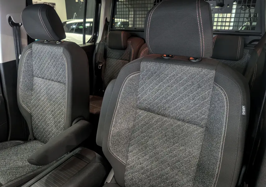 Gros plan sur les sièges avant en tissu gris et noir du Peugeot Rifter 2025, version Allure, avec surpiqûres contrastantes.