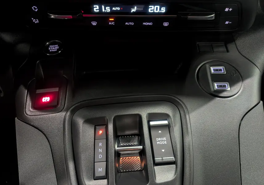 Gros plan sur la console centrale intérieure du Peugeot Rifter 2025 noir, avec levier de vitesses automatique et commandes climatisation.