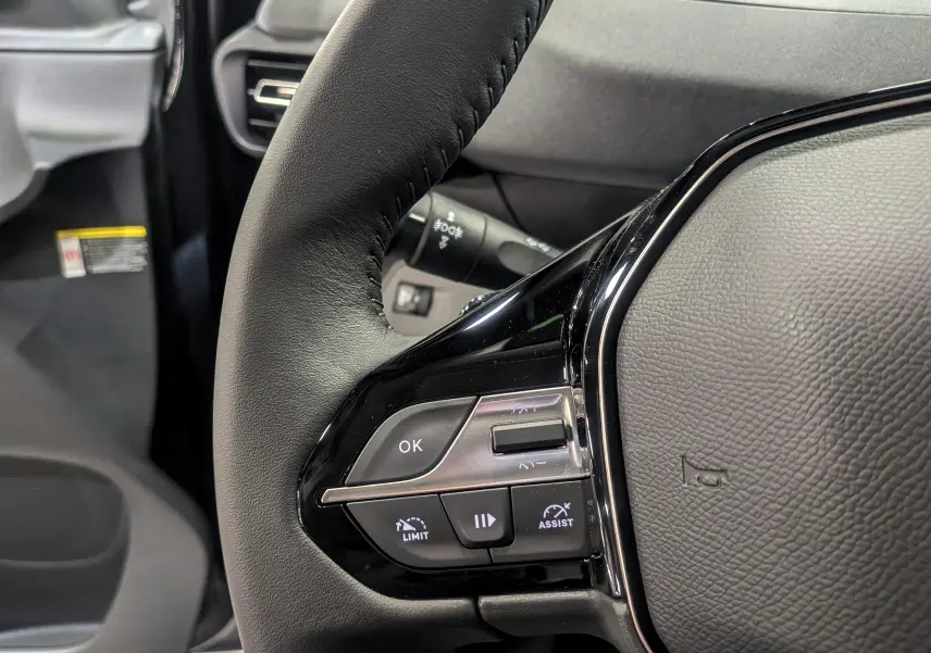 Gros plan sur le volant noir du Peugeot Rifter 2025, avec commandes intégrées et détails en plastique brillant.