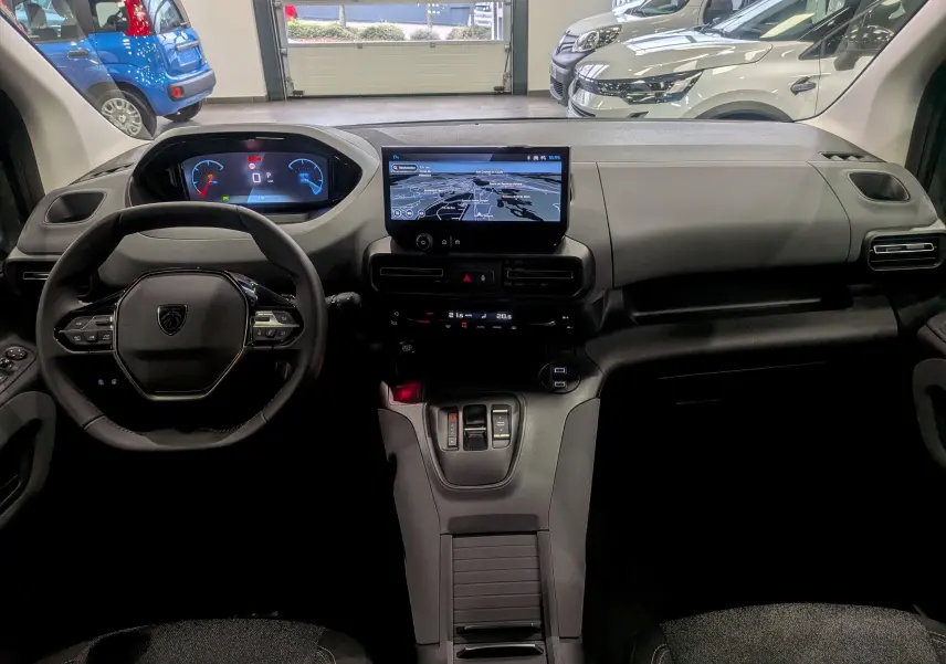 Vue intérieure avant du Peugeot Rifter 2025 noir, avec tableau de bord numérique et écran tactile central affichant la navigation.