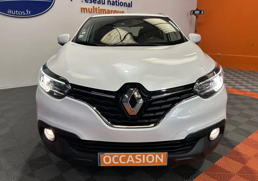 Vue avant d'un Renault Kadjar blanc 2018 avec phares allumés et plaque "OCCASION" en orange.