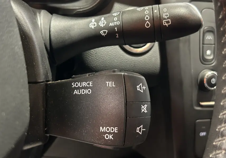 Gros plan sur les commandes audio et essuie-glace à gauche du volant dans un Renault Kadjar blanc de 2018.