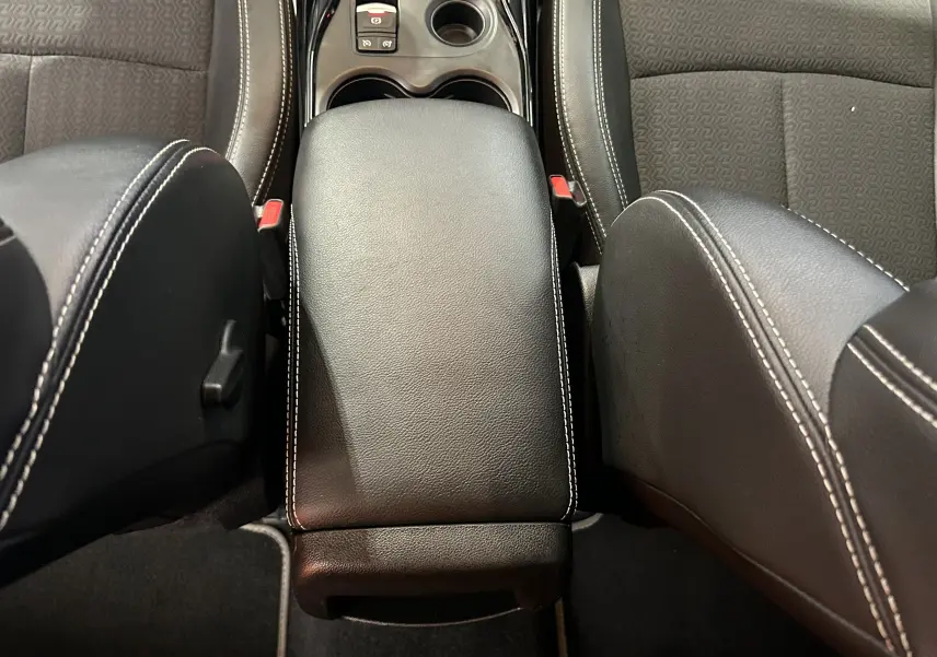 Vue intérieure centrée sur l'accoudoir noir en cuir avec surpiqûres blanches entre les sièges avant gris du Renault Kadjar.