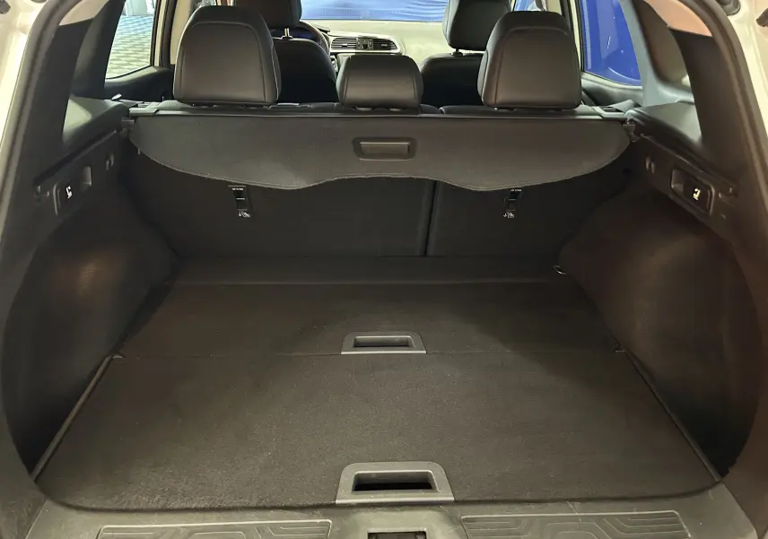 Vue intérieure du coffre spacieux du Renault Kadjar blanc, avec banquette arrière et cache-bagages visibles.