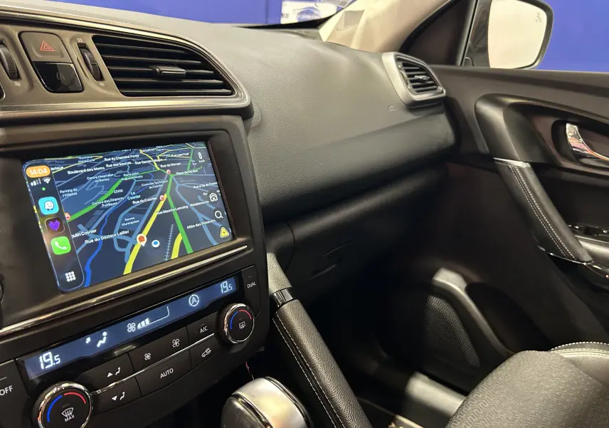 Vue intérieure côté passager du tableau de bord noir du Renault Kadjar blanc, avec écran tactile affichant la navigation.