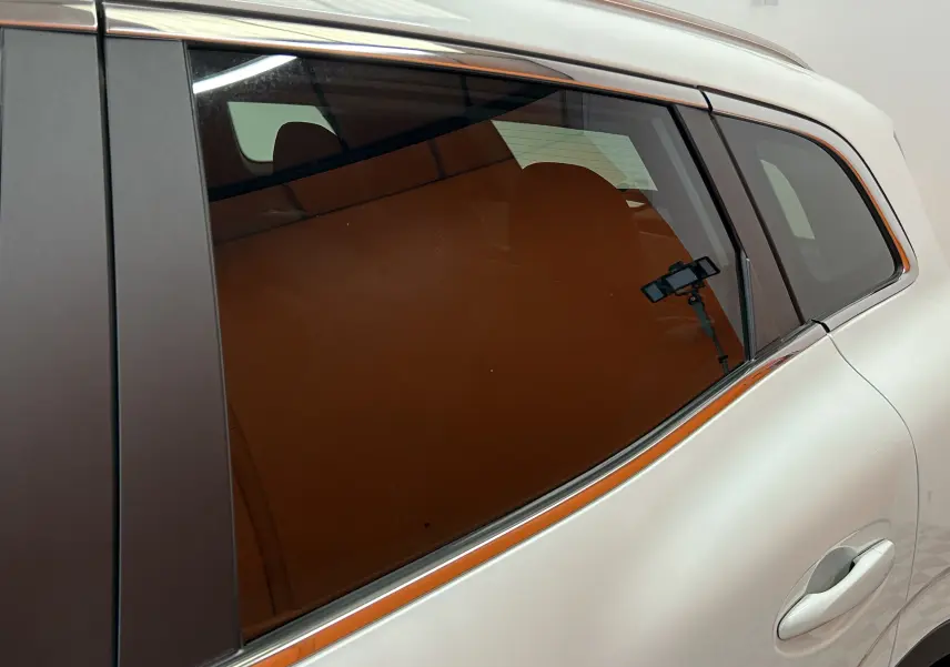 Détail de la vitre arrière côté droit du Renault Kadjar blanc 2018 avec reflet d’un support de smartphone.