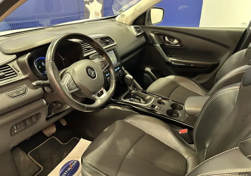 Vue intérieure côté conducteur du Renault Kadjar blanc 2018, avec volant cuir et console centrale brillante.