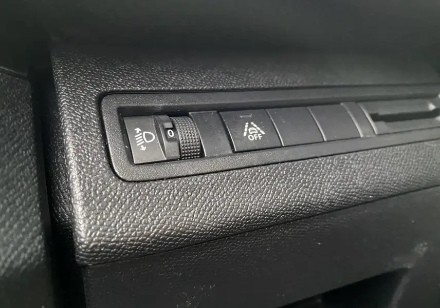 Gros plan sur les commandes de réglage des phares et d'aide à la conduite du tableau de bord d'un Peugeot 3008 gris platinium.