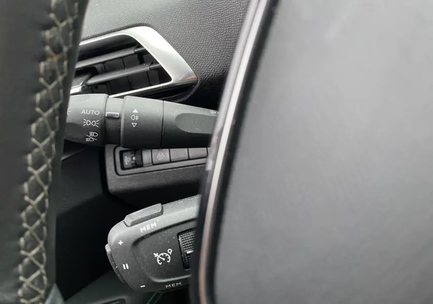 Détail du volant et commandes de régulateur de vitesse sur Peugeot 3008 gris platinium, vue intérieure côté conducteur.