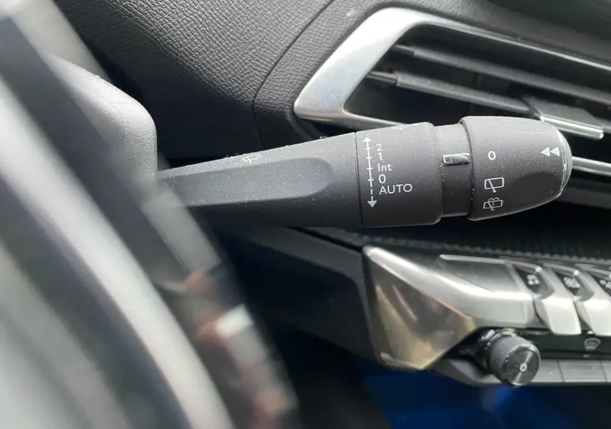 Gros plan sur la commande d’essuie-glace à gauche du volant du Peugeot 3008 gris platinium, intérieur noir.