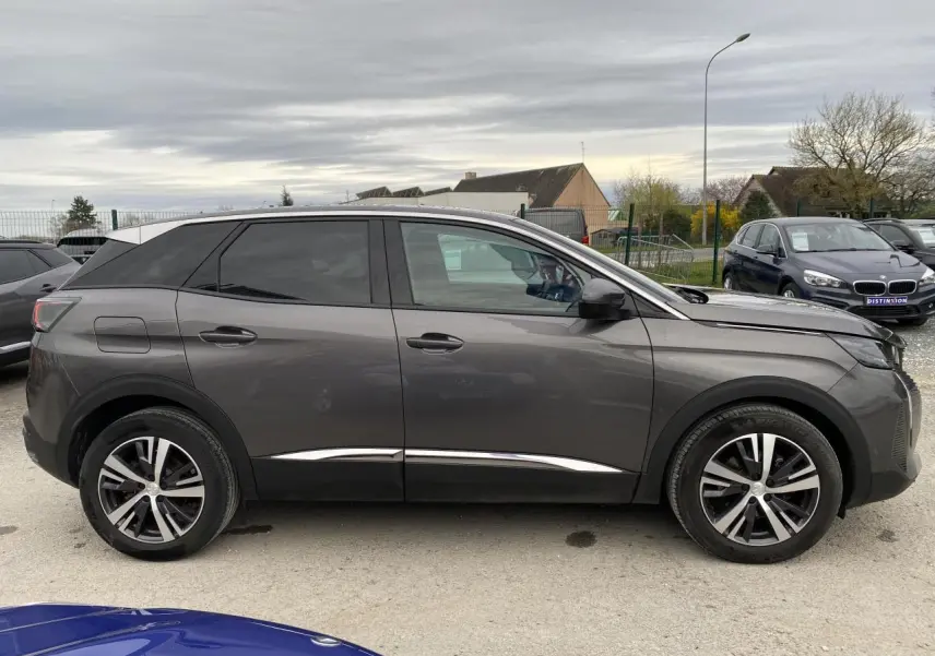 Profil droit d’un Peugeot 3008 gris platinium 2021 avec jantes alliage et vitres teintées, garé en extérieur.