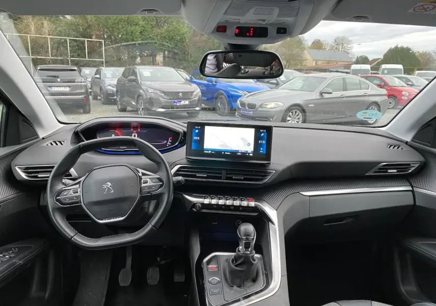 Vue intérieure avant du Peugeot 3008 gris platinium 2021, volant compact, écran tactile GPS et boîte manuelle visible.
