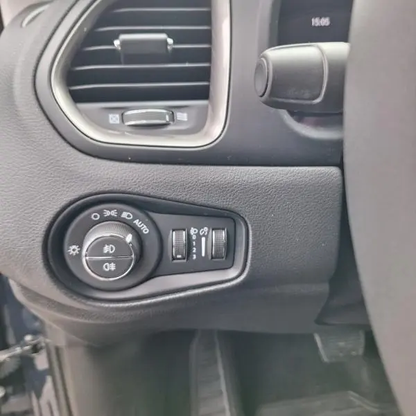 Détail du tableau de bord côté gauche d’un Jeep Renegade bleu 2024, avec commandes des phares et ventilation.