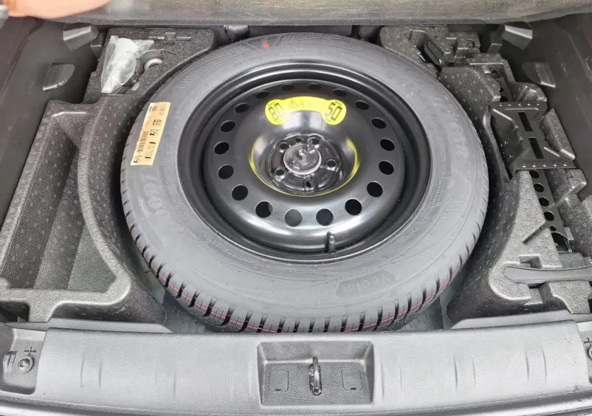 Vue plongeante sur la roue de secours noire et ses outils de bord dans le coffre du Jeep Renegade 2024.