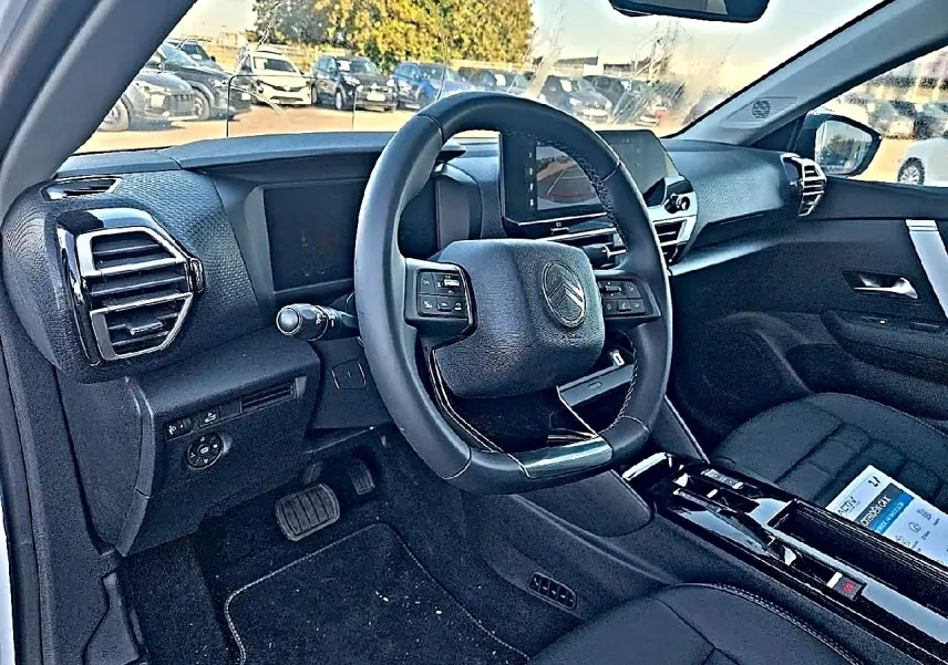 Intérieur noir de la Citroën C4 X 2025 vu côté conducteur, avec volant cuir et écran tactile central.