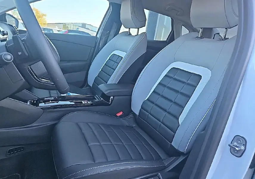 Vue intérieure côté conducteur de la Citroën C4 X blanche, sièges bi-ton noir et gris avec accoudoir central.