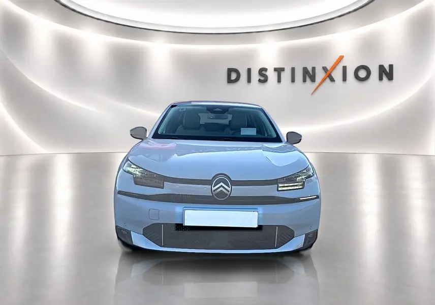 Vue avant d'une Citroën C4 X blanche 2025, avec logo distinctif et éclairage LED moderne dans un showroom lumineux.