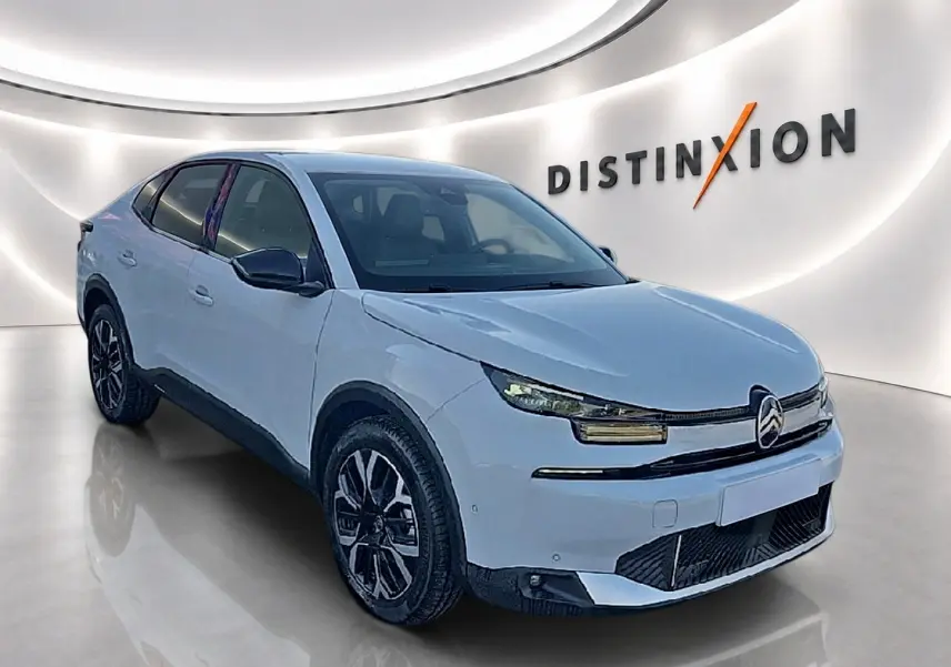 Vue 3/4 avant d'une Citroën C4 X blanche avec jantes alu noires, dans un showroom lumineux au logo Distinxion.