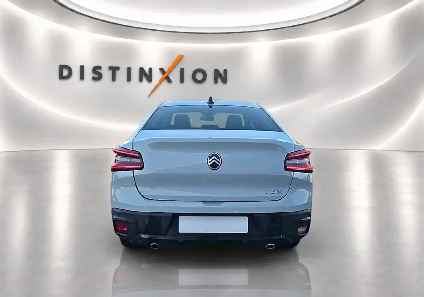 Vue arrière d'une Citroën C4 X blanche 2025 dans un showroom lumineux avec double sortie d'échappement chromée.