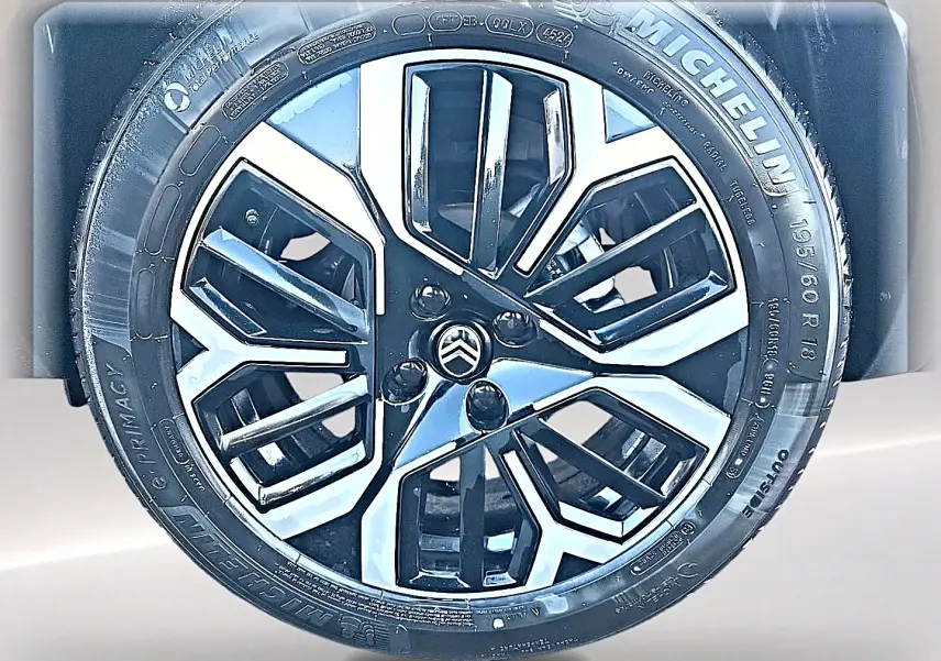 Gros plan sur la jante alu noire et argentée avec logo Citroën, montée sur pneu Michelin, carrosserie blanche visible en arrière-plan.