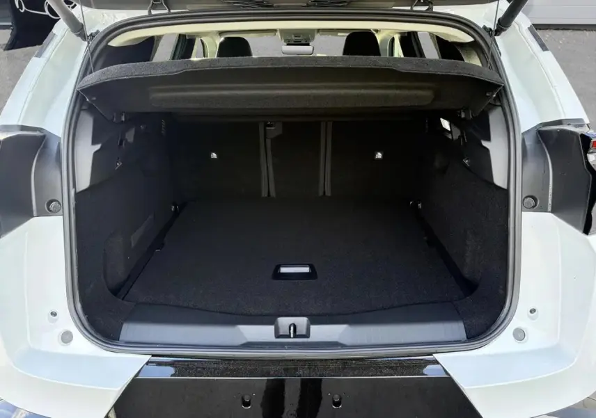Coffre ouvert d'un Citroën C5 Aircross blanc, vue arrière montrant l'espace de chargement et la plage arrière relevée.