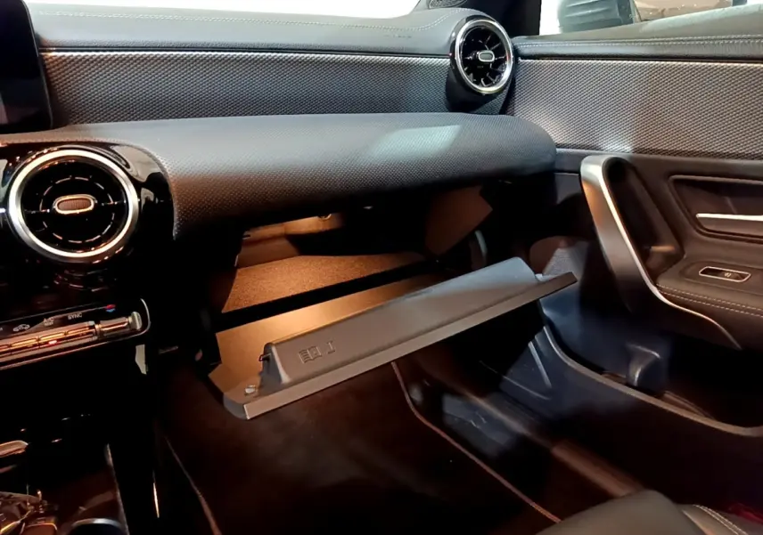 Intérieur de la Mercedes CLA 180 d Business Line 2021, vue côté passager avec boîte à gants ouverte et tableau de bord noir.