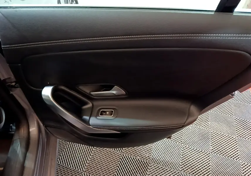 Vue intérieure de la porte côté gauche en cuir noir avec surpiqûres blanches d'une Mercedes CLA 180 d Business Line 2021.