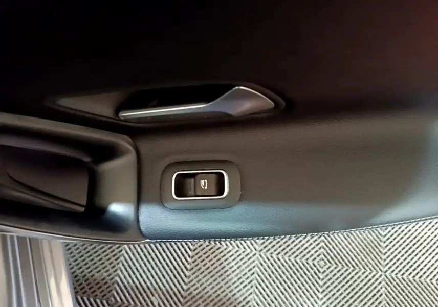Détail de la commande d'ouverture du coffre sur la portière intérieure noire d'une Mercedes CLA 180 d Business Line.