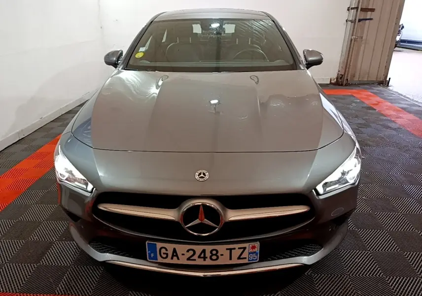 Vue avant d'une Mercedes CLA 180 d Business Line gris clair, avec phares LED allumés dans un garage.