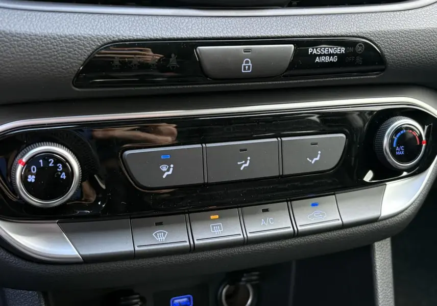 Détail de la console centrale de la Hyundai i30 SW T-GDI 120 Modern 2025, avec commandes de climatisation manuelle et boutons rétroéclairés.