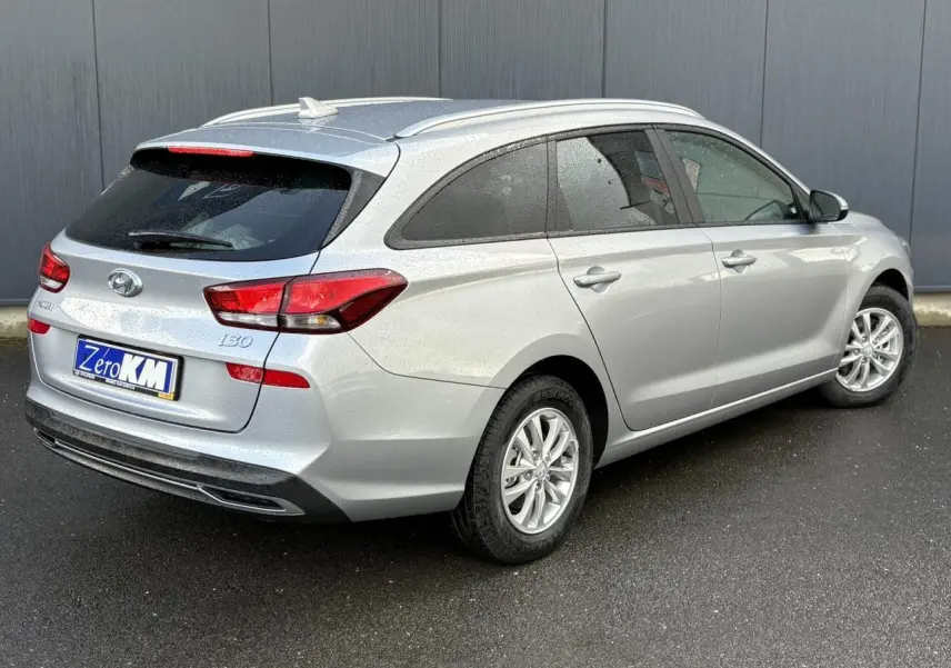 Vue 3/4 arrière droite d'une Hyundai i30 SW T-GDI 120 Modern gris argent métallisé avec vitres surteintées et rails de toit.