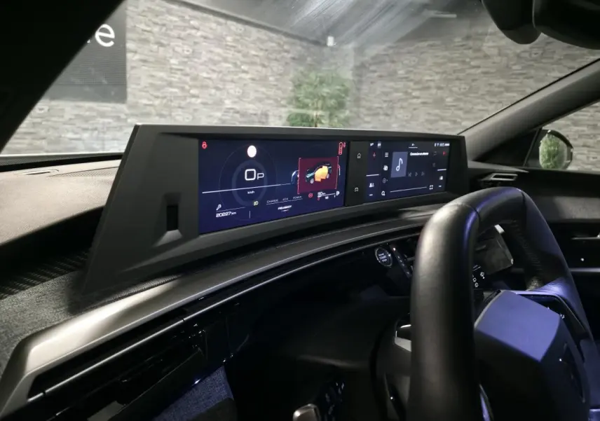 Vue intérieure du tableau de bord du Peugeot 5008 blanc 2025, avec double écran HD panoramique et volant compact cuir noir.