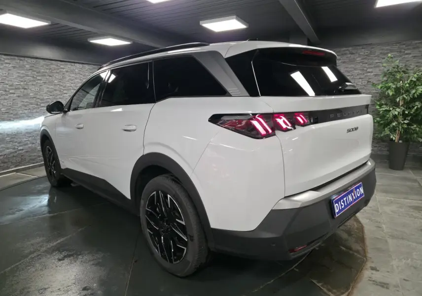 Peugeot 5008 blanc en 3/4 arrière droit, feux arrière LED 3 griffes et jantes alliage noires brillantes.