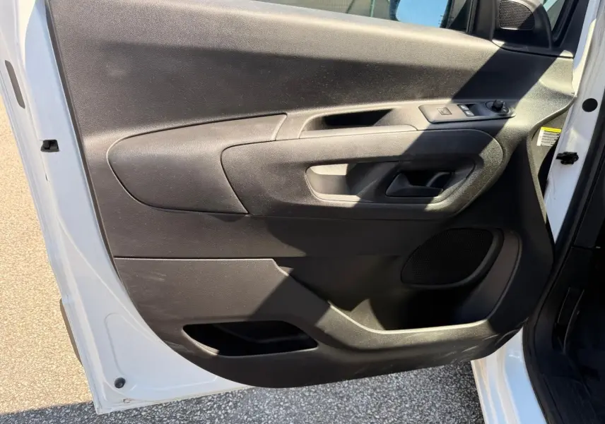 Vue intérieure de la porte avant gauche du Citroën Berlingo blanc, avec commandes de vitres et poignée noire.