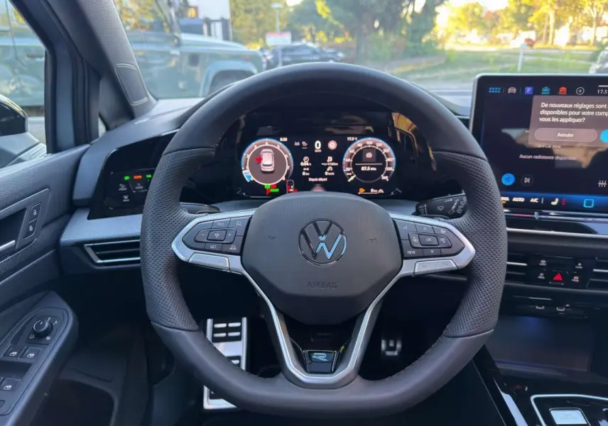 Vue centrée sur le volant cuir multifonctions de la Volkswagen Golf E-TSI 150 R-Line avec tableau de bord numérique.