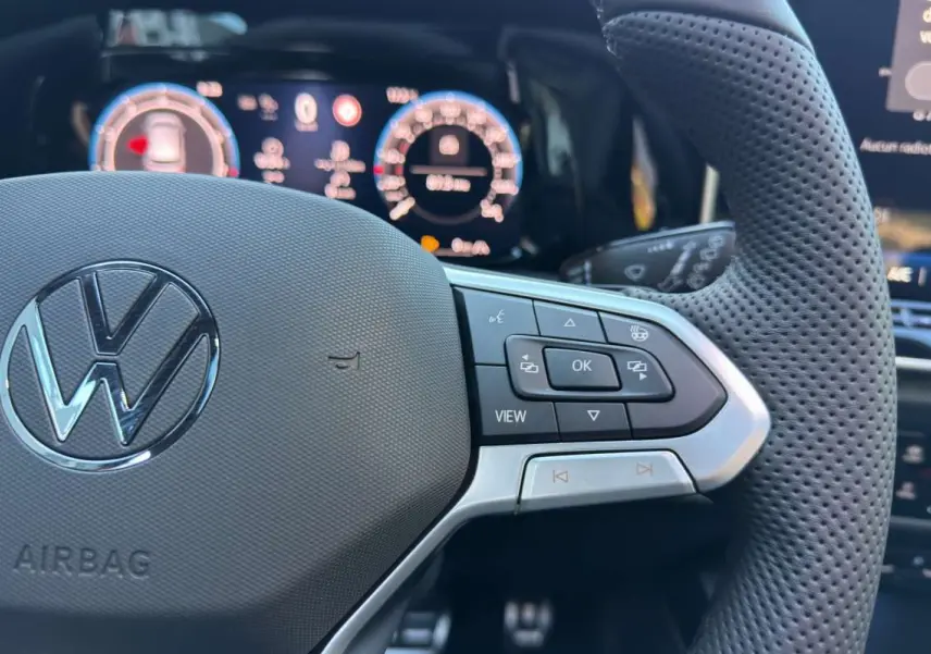 Gros plan sur le volant cuir perforé côté droit de la Volkswagen Golf E-TSI 150 R-Line avec commandes multifonctions.