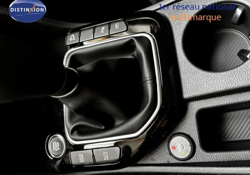 Gros plan sur la console centrale noire du Kia Sportage blanc nacré, montrant le levier de vitesse manuel et les boutons de contrôle.