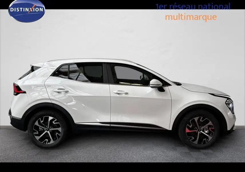 Profil latéral droit d’un KIA SPORTAGE blanc nacré métal 2025 avec jantes alliage noires et détails rouges.