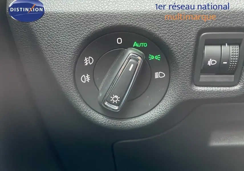 Gros plan sur le bouton de commande des phares dans l'habitacle d'une Skoda Kamiq rouge Velvet Metal 2024.