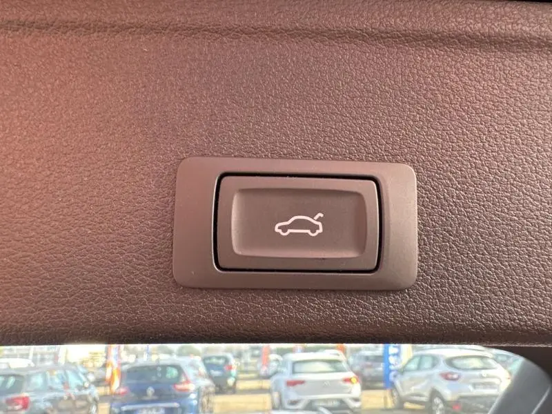 Bouton d'ouverture électrique du coffre sur la garniture intérieure d'une Audi A4 Avant noire, vue rapprochée.