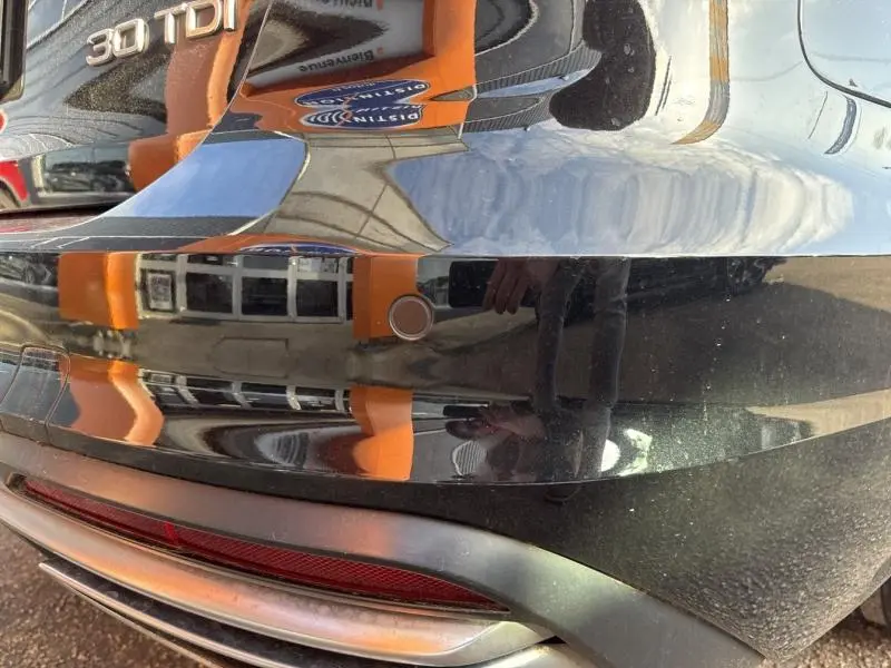 Gros plan sur le pare-chocs arrière noir brillant de l'Audi A4 Avant 30 TDI avec capteur de stationnement visible.