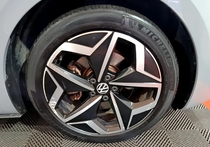 Gros plan sur la roue avant gauche d’un Volkswagen ID.3 gris foncé avec jante alliage noire et argentée.
