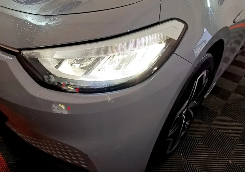 Gros plan sur le phare avant droit allumé d'une Volkswagen ID.3 77 kWh Pro S gris foncé avec jante noire.