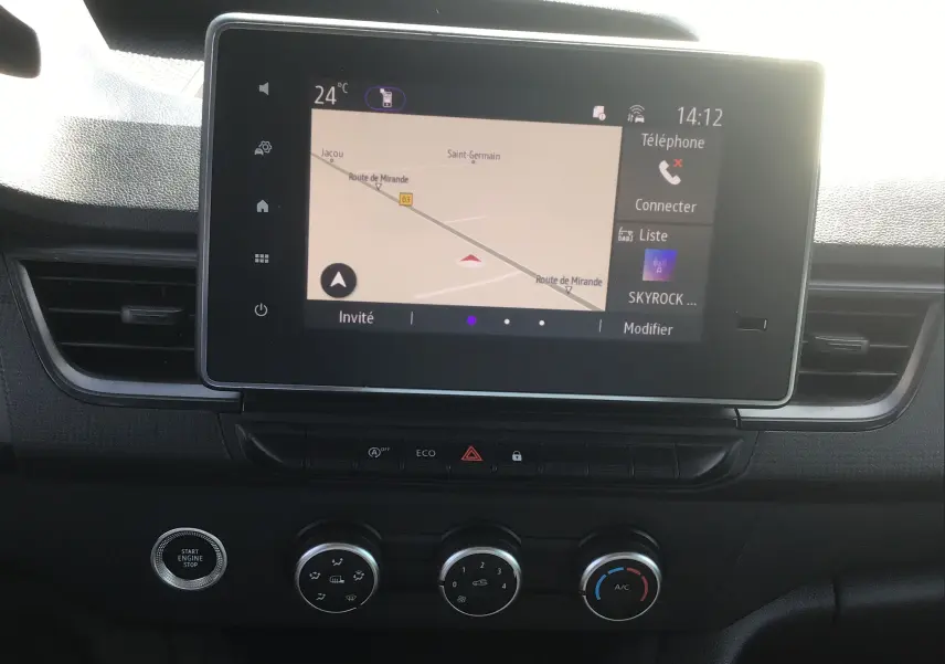 Vue rapprochée de l’écran tactile central du Renault Kangoo 2024 blanc, affichant la navigation et les commandes climatisation.